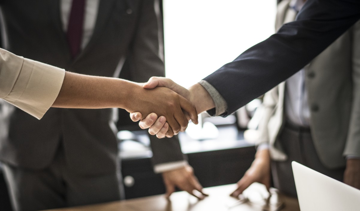 man and woman shaking hands over table with two others looking on340877989